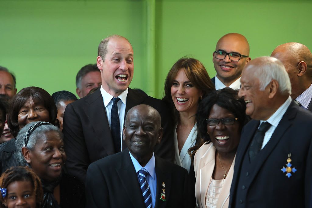 William and Kate laugh with members from the Windrush Cymru Elders after the prince made a joke while posing for a picture during a visit to the Grange Pavilion